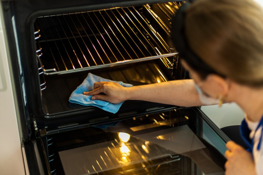 woman  in gloves cleaning oven