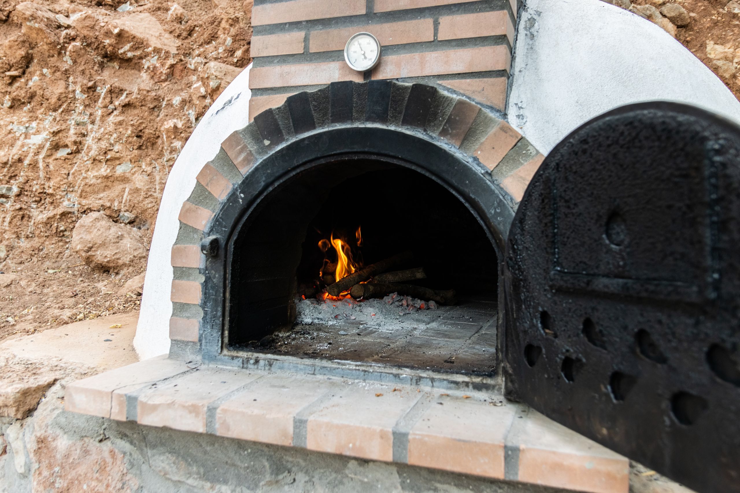 wood oven built on the outside with the door open and fire inside