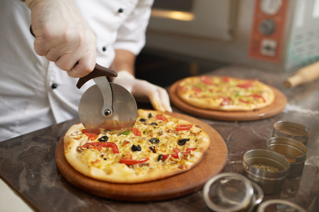 Chef cuts freshly prepared pizza slices