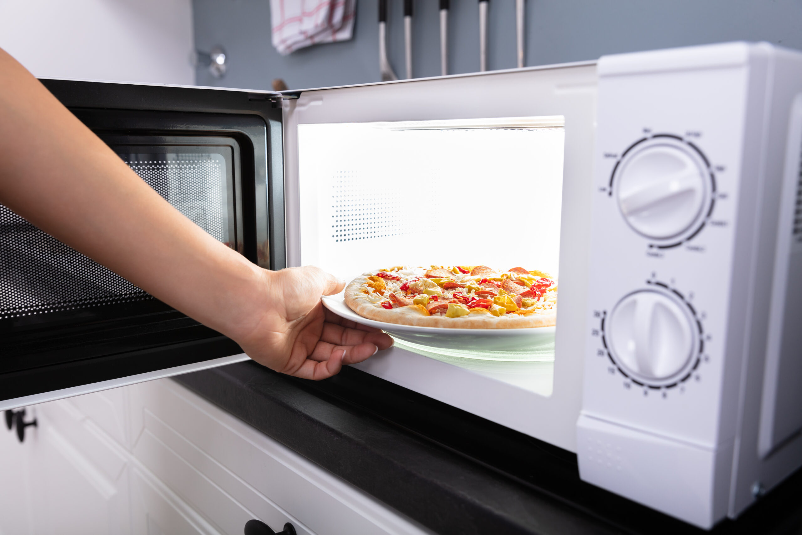 A Happy Woman Baking Pizza In Microwave Oven