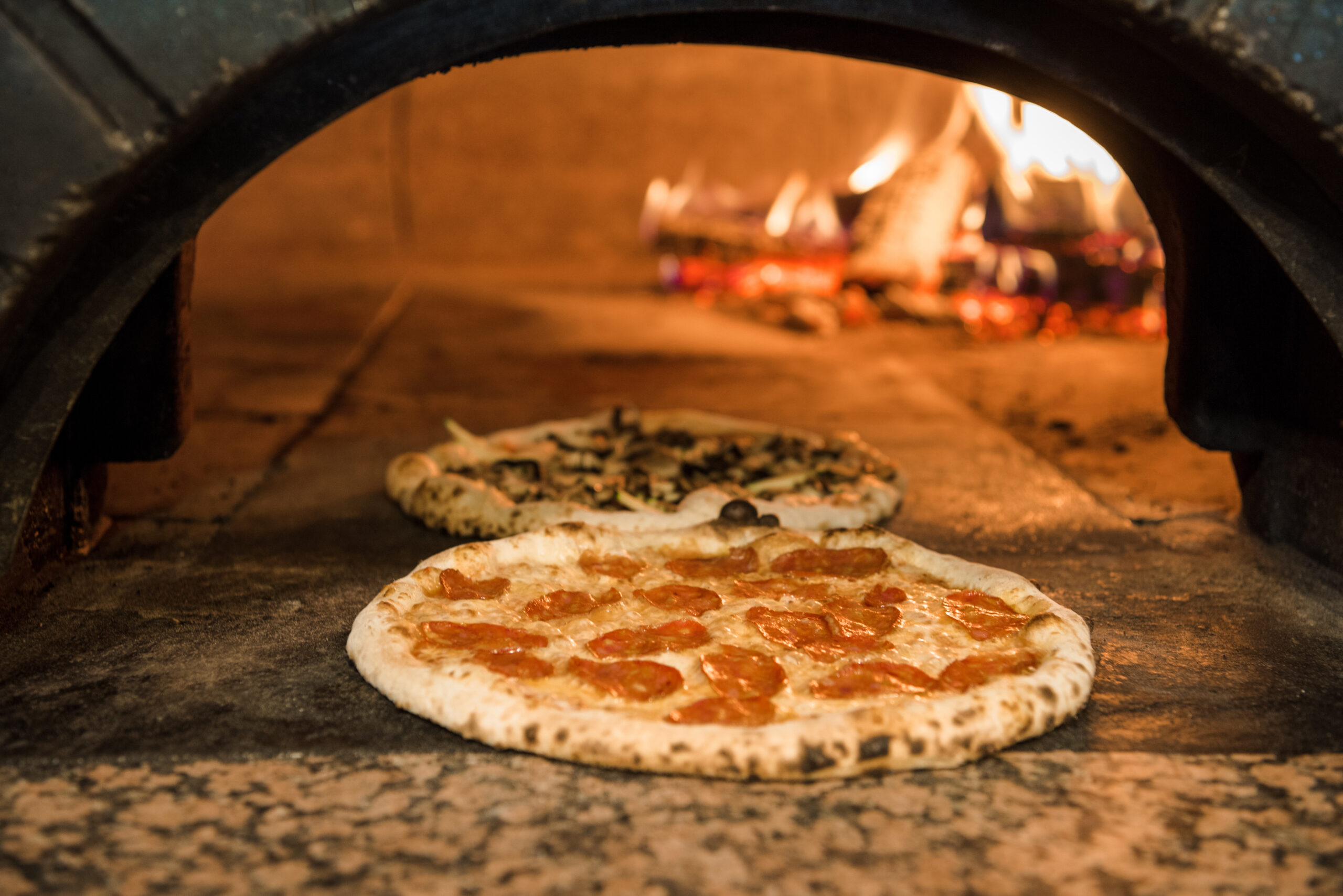 close up view of italian pizza baking in brick oven in restaurant