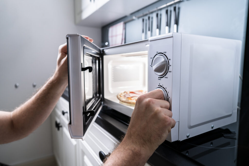 Human Hand Baking Pizza In Microwave Oven set time and temperature