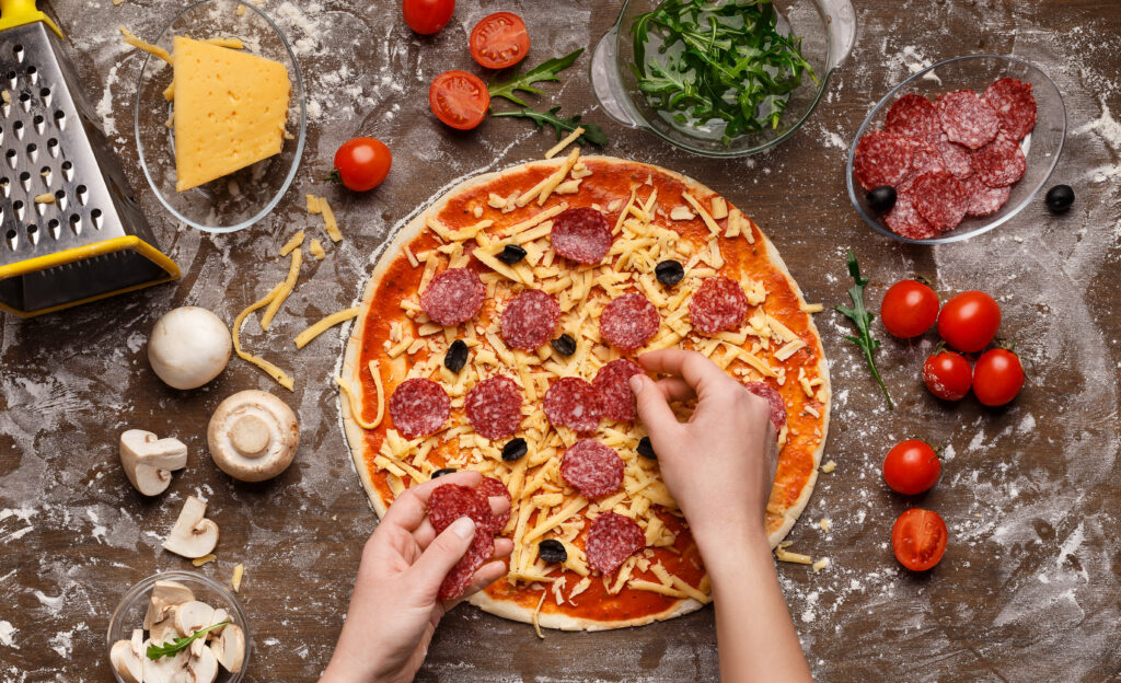 Pepperoni Pizza assembling Woman Adding Salami And Olives To Pizza