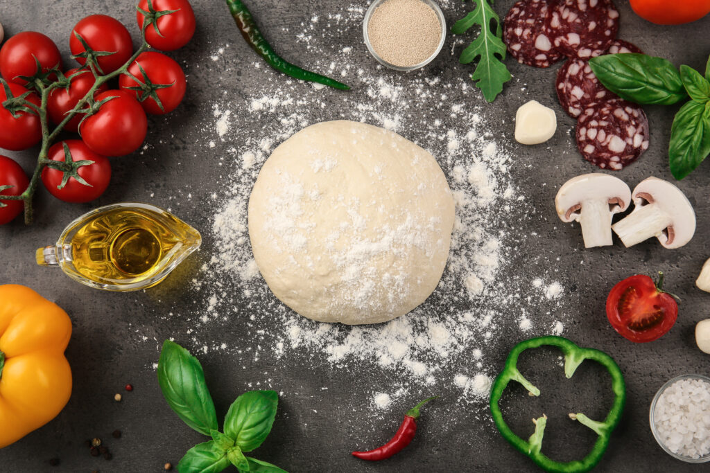 Raw dough for pizza with ingredients