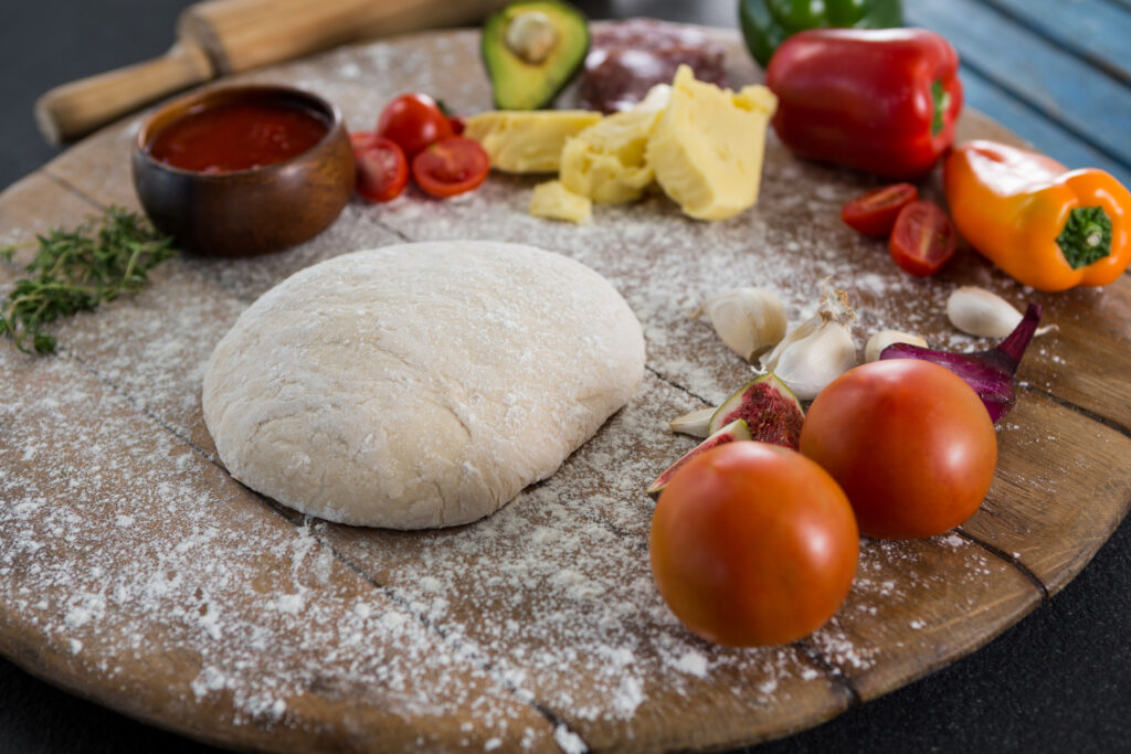Various ingredients with pizza dough and flour