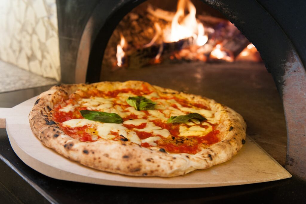 margherita pizza baking in wooden pizza oven