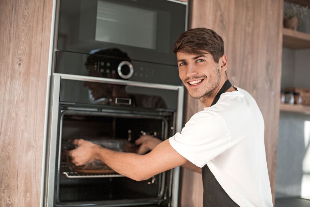 young man standing on a electric pizza oven