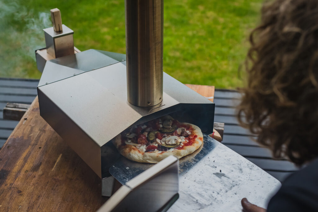 Man is pulling a delicious home made pizza in gas pizza oven