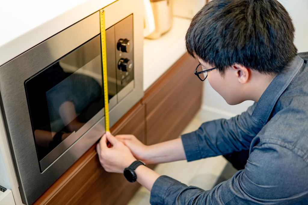 man using tape measuring the size and space of oven