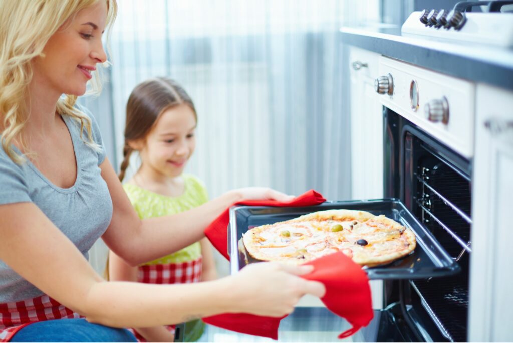 mother and daughter baking pizza 